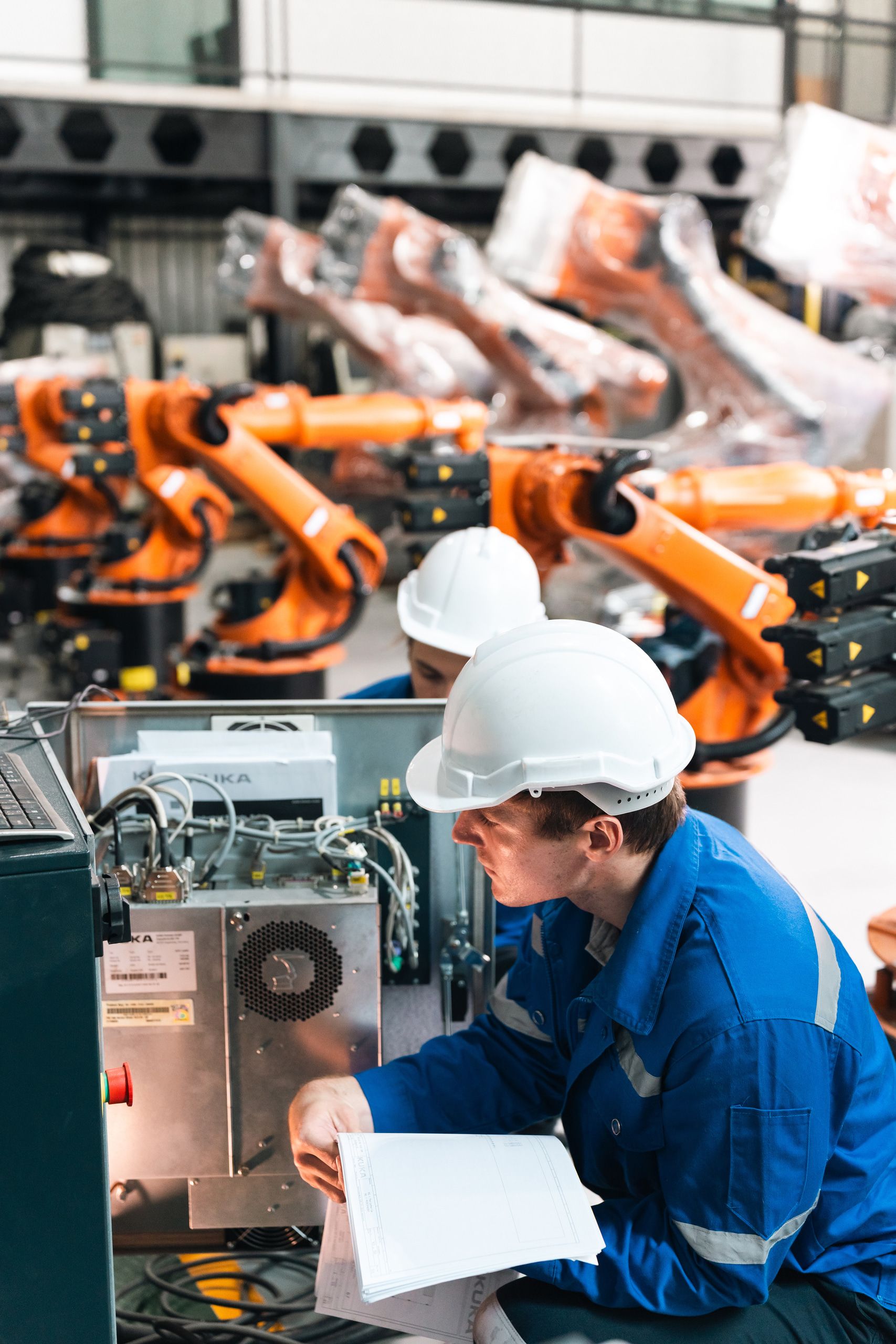 Engineers inspecting industrial robot arm in factory automation technology innovation smart manufacturing global industry expert analysis robotics system quality control