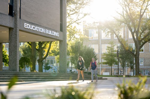 Two students walk past Education Building