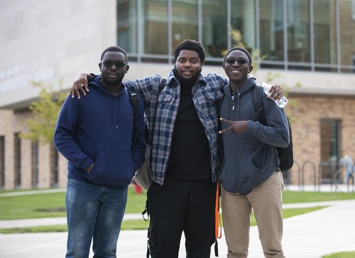 Three students standing together outside the Maurer Center