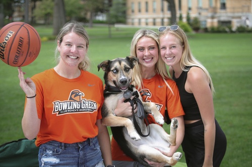 Three students pose with dog