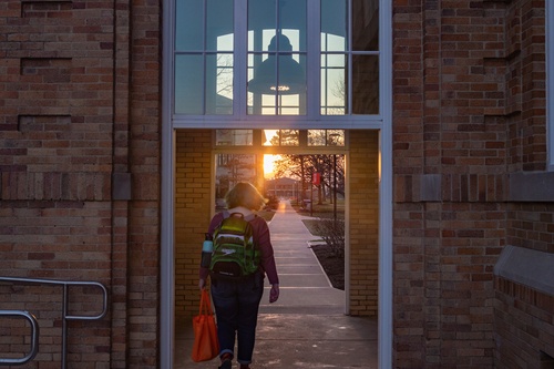 Student passing through walkway between University Hall and the Maurer Center