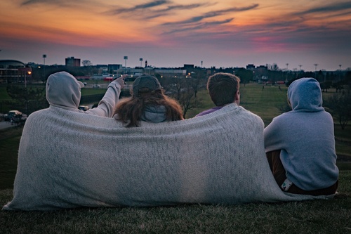 Two students watch the sunset from the hill near the Sebo Center