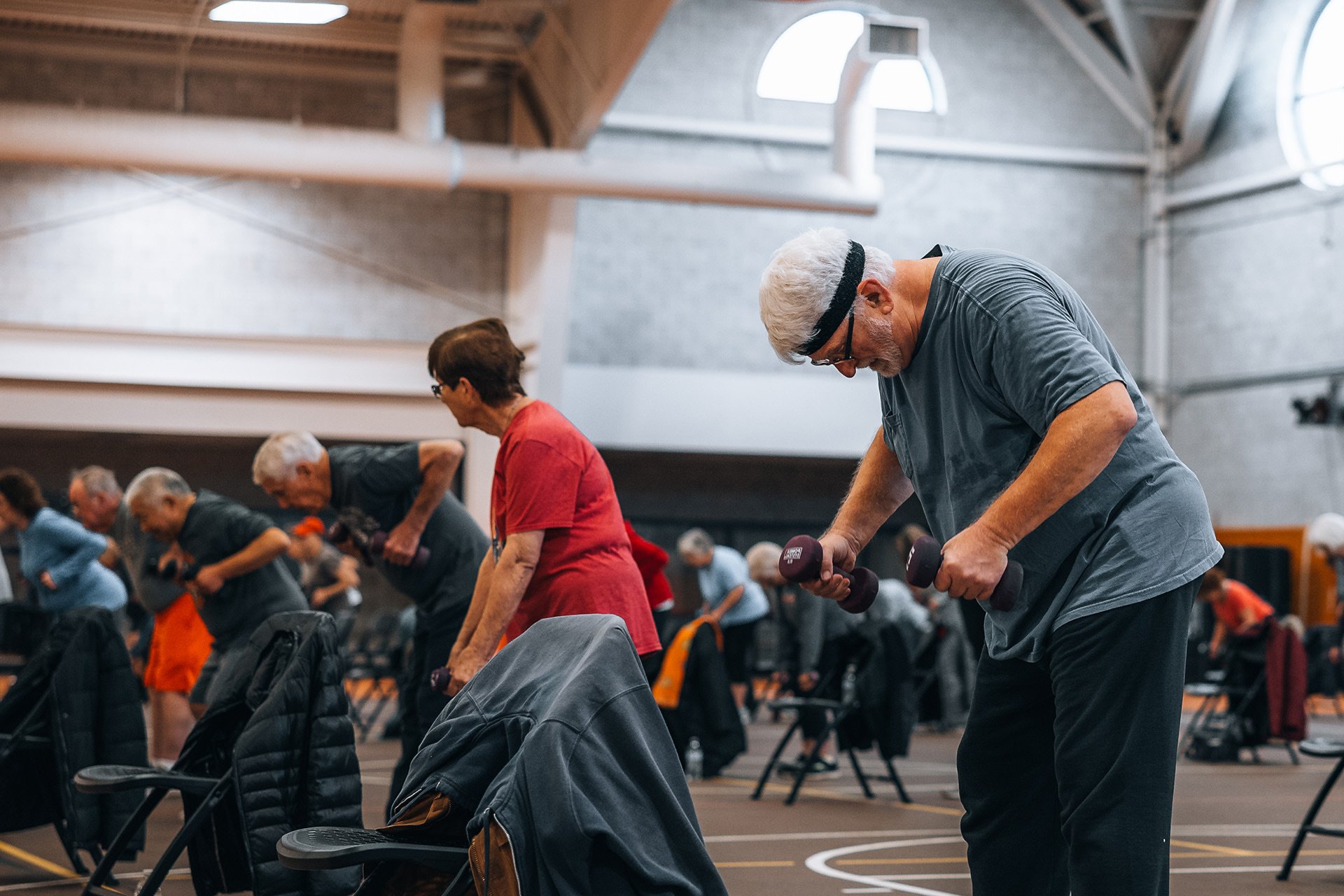 a group of older adults participating in a dumbbell weight class doing reverse fly exercise