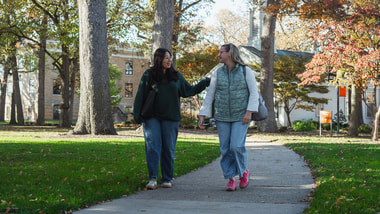 two girls walking on a sidewalk through campus