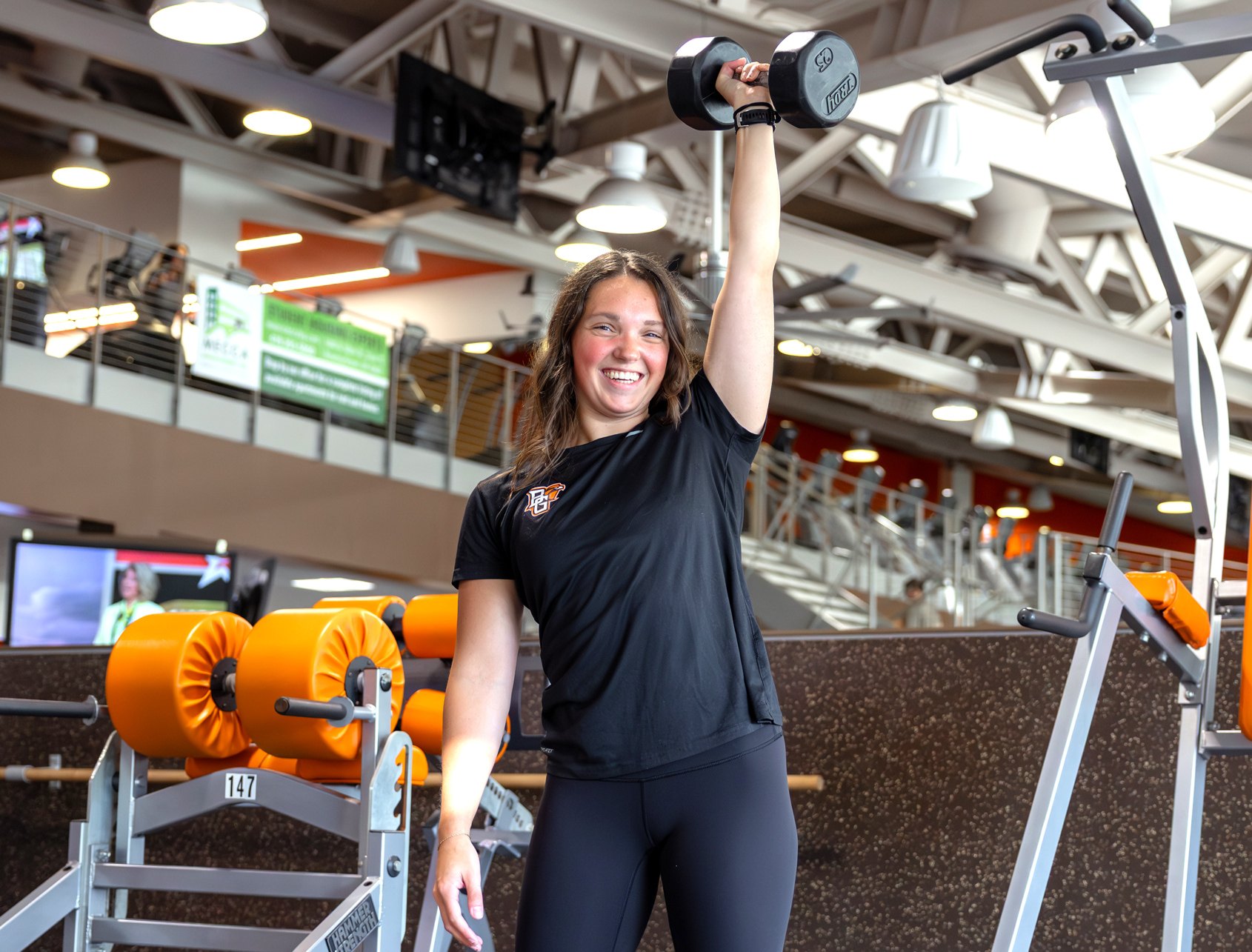 smiling girl doing a snatch with a dumbell