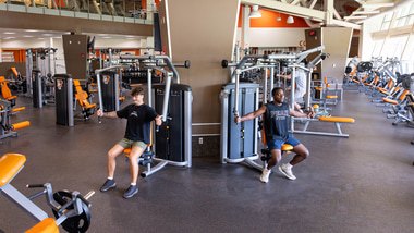 two people using weight machines in a gym