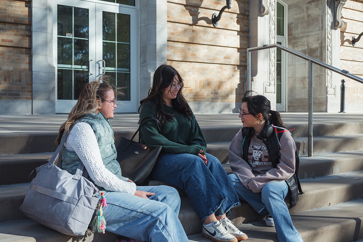 Three girls sitting on steps talking with each other