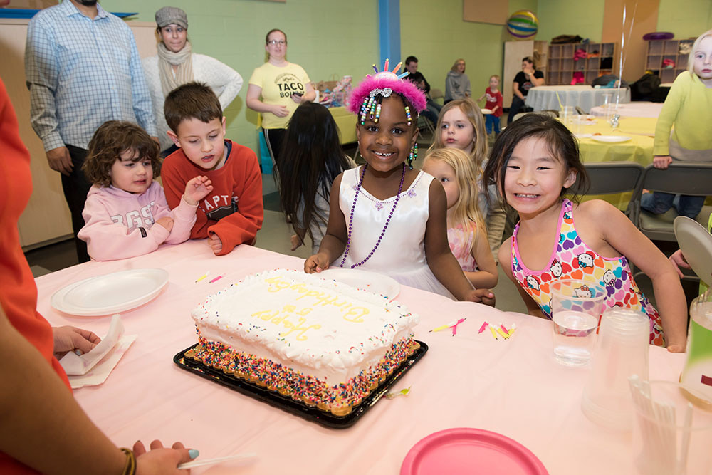 kids standing in front of a birthday cake at a birthday party
