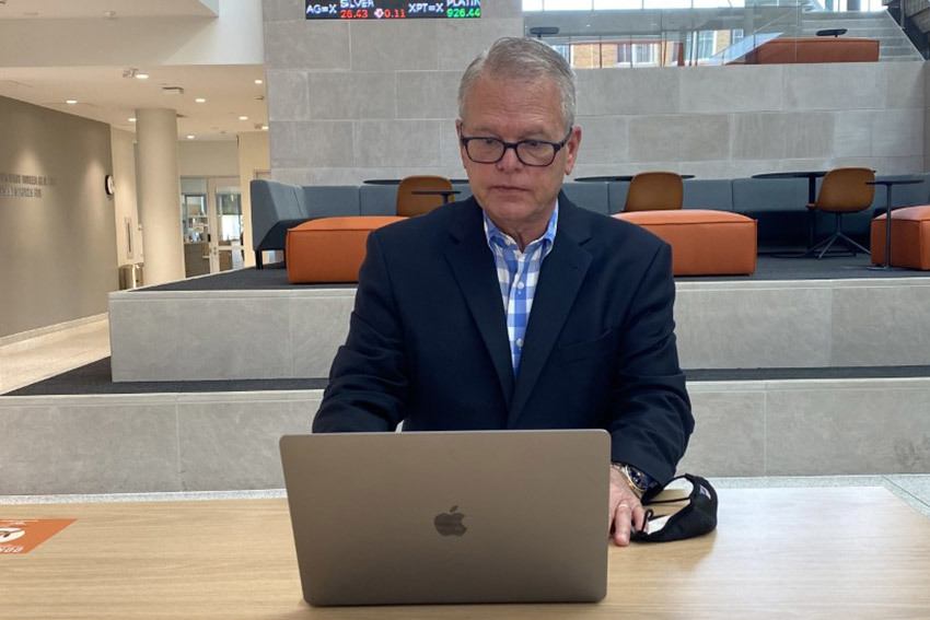 Dean Ray Braun on a laptop in the atrium of the Maurer Center